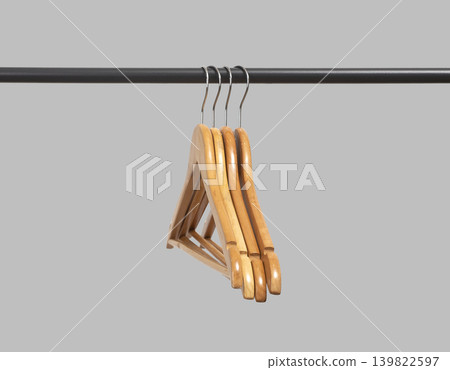 Wooden hangers stacked vertically on black metal rack. Garment holders aligned on horizontal bar. Interior organization setup for wardrobe, retail, storage concept.. Wooden hangers stacked vertically on black metal rack. Garment holders aligned on horizontal bar. Interior organization setup for wardrobe, retail, storage concept.. 139822597