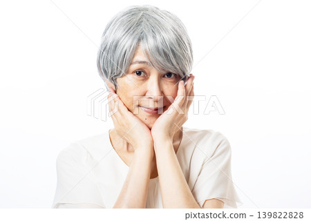 A senior woman touches her cheek to check the condition of her skin. A senior woman touches her cheek to check the condition of her skin. 139822828