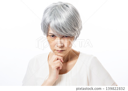一位老婦人手托下巴，表情嚴肅。 139822832