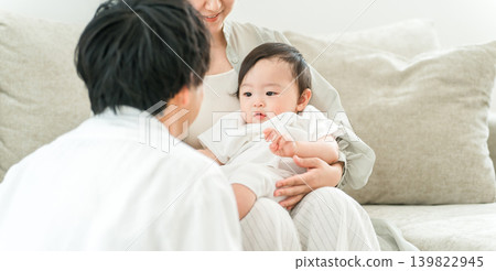 A young family spending time with their baby on the living room sofa in their home A young family spending time with their baby on the living room sofa in their home 139822945