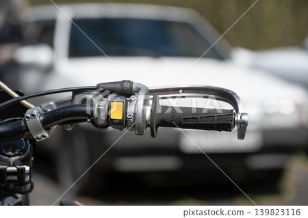 Close-up of a motorcycle handlebar with controls and yellow switch. Close-up of a motorcycle handlebar with controls and yellow switch. 139823116