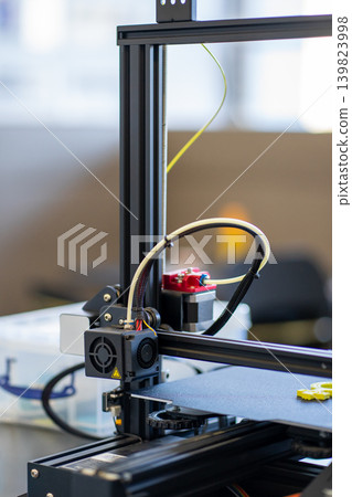 View of a working 3D printer mechanism printing a plastic part View of a working 3D printer mechanism printing a plastic part 139823998