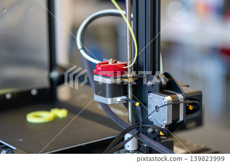 A small 3D printer that prints a green symbol out of plastic A small 3D printer that prints a green symbol out of plastic 139823999