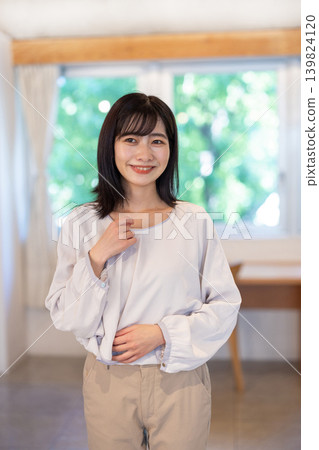 A young Japanese woman smiles at the camera in a brightly lit room. A young Japanese woman smiles at the camera in a brightly lit room. 139824120