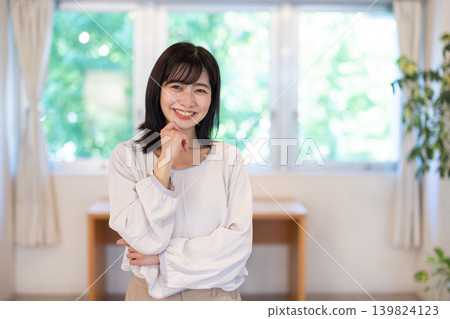 A young Japanese woman smiles at the camera in a brightly lit room. A young Japanese woman smiles at the camera in a brightly lit room. 139824123