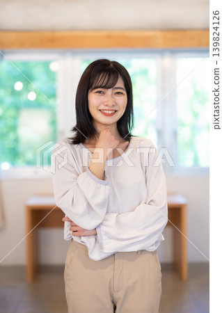 A young Japanese woman smiles at the camera in a brightly lit room. A young Japanese woman smiles at the camera in a brightly lit room. 139824126