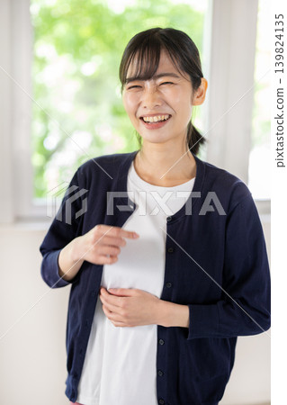 A young Japanese woman smiles at the camera in a brightly lit room. A young Japanese woman smiles at the camera in a brightly lit room. 139824135