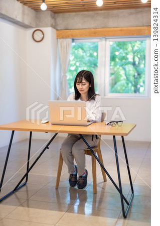 A young Japanese woman working on a computer at her desk. A young Japanese woman working on a computer at her desk. 139824314