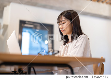A young Japanese woman working on a computer at her desk. A young Japanese woman working on a computer at her desk. 139824317