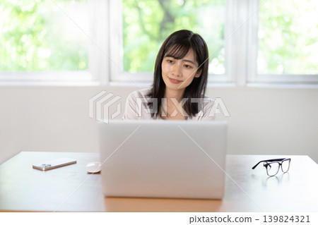 A young Japanese woman working on a computer at her desk. A young Japanese woman working on a computer at her desk. 139824321