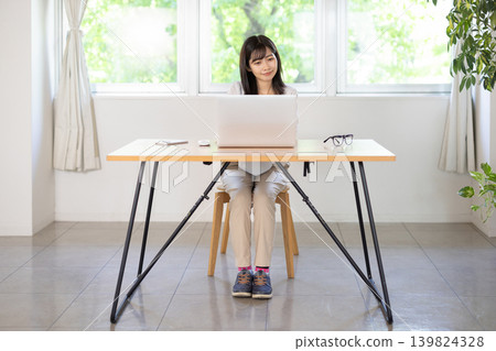 A young Japanese woman working on a computer at her desk. A young Japanese woman working on a computer at her desk. 139824328
