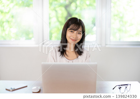 一位年輕的日本女性正在辦公桌前使用電腦。 139824330