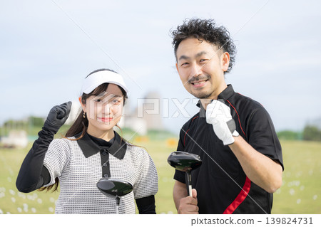 一張照片顯示,一位女士正在上高爾夫球課,她面帶微笑,擺出勝利的姿勢,和她的高爾夫球教練一起看向鏡頭。 一張照片顯示,一位女士正在上高爾夫球課,她面帶微笑,擺出勝利的姿勢,和她的高爾夫球教練一起看向鏡頭。 139824731