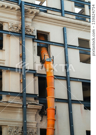 Waste chute used in construction demolition garbage. Suspended sections of a construction garbage chute on the facade of a historic building undergoing renovation. Safe waste disposal. 139824754