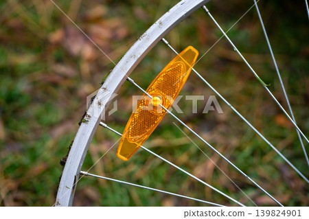 View of a broken bicycle wheel with orange warning reflector View of a broken bicycle wheel with orange warning reflector 139824901