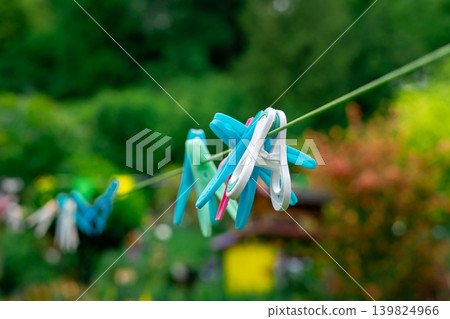 Multi-colored clothespins hang on a rope in the yard. Washing and drying clothes Multi-colored clothespins hang on a rope in the yard. Washing and drying clothes 139824966