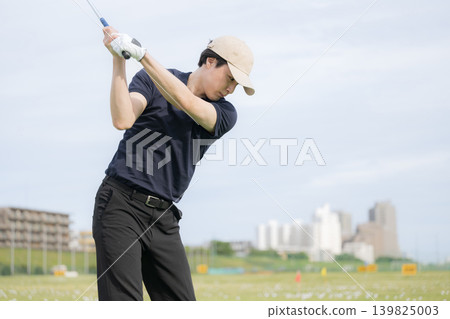 一張男性高爾夫球手在練習場揮桿擊球的運動照片。 一張男性高爾夫球手在練習場揮桿擊球的運動照片。 139825003