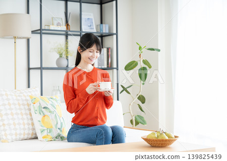 Middle woman drinking coffee in the living room 139825439