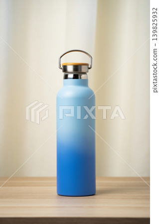 A sleek blue insulated stainless steel water bottle with bamboo cap, designed for reusable everyday hydration and travel. Minimalist matte ombre gradient finish and durable build make it ideal for gym 139825932
