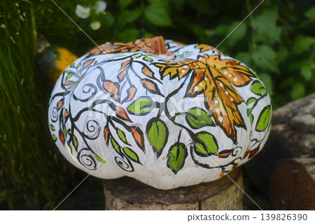A white pumpkin displays hand-painted vine and leaf decorations A white pumpkin displays hand-painted vine and leaf decorations 139826390