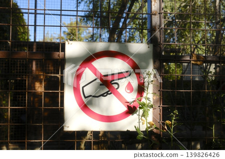 A red and white prohibition sign is attached to a wire fence outside A red and white prohibition sign is attached to a wire fence outside 139826426