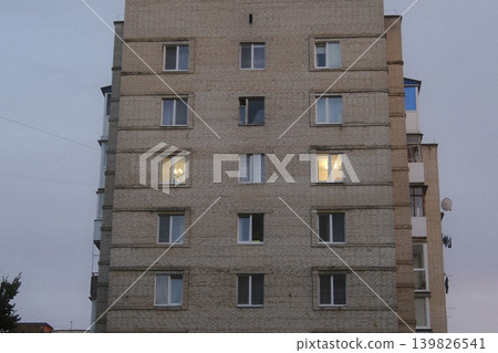 Brick apartment building has lighted windows. It looks like dusk in the City Brick apartment building has lighted windows. It looks like dusk in the City 139826541