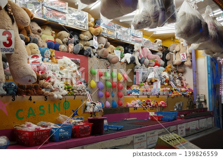 A carnival game booth is lined with stuffed animal prizes and colorful balloons A carnival game booth is lined with stuffed animal prizes and colorful balloons 139826559
