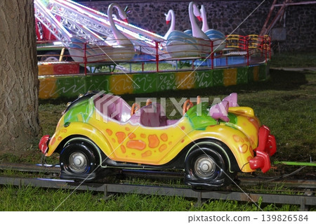 Two carnival rides are seen. The front is a car train Two carnival rides are seen. The front is a car train 139826584