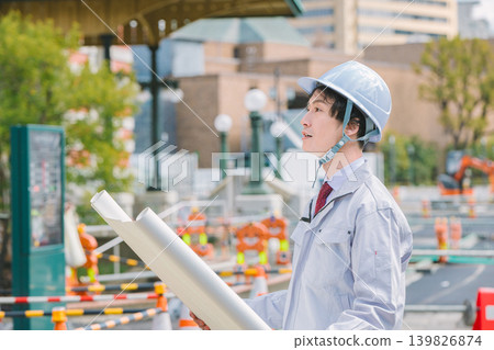 Site supervisor checking blueprints during road construction. 139826874