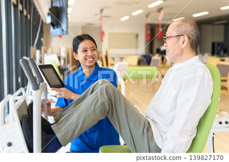 Seniors doing lower body strength training and foreign caregivers Seniors doing lower body strength training and foreign caregivers 139827170