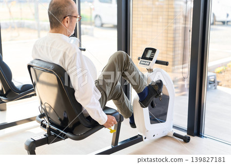 Seniors doing lower body strength training on an exercise bike Seniors doing lower body strength training on an exercise bike 139827181