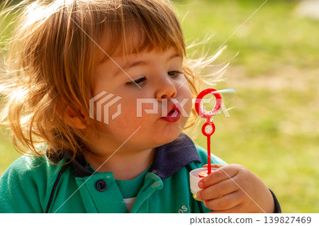 Cute Toddler Girl Blowing Soap Bubbles Outdoors in Sunshine Cute Toddler Girl Blowing Soap Bubbles Outdoors in Sunshine 139827469
