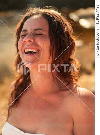 Happy brunette woman enjoying golden hour light by the water in nature Happy brunette woman enjoying golden hour light by the water in nature 139827785