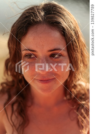 Portrait of young woman in nature at golden hour with relaxed and playful expression 139827789