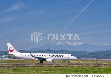 Sendai Airport on a sunny day: Zao mountain range and a taxiing airplane. Natori City, Miyagi Prefecture. Sendai Airport on a sunny day: Zao mountain range and a taxiing airplane. Natori City, Miyagi Prefecture. 139827795