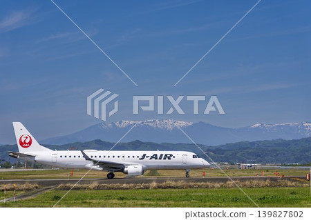 Sendai Airport on a sunny day: Zao mountain range and a taxiing airplane. Natori City, Miyagi Prefecture. Sendai Airport on a sunny day: Zao mountain range and a taxiing airplane. Natori City, Miyagi Prefecture. 139827802