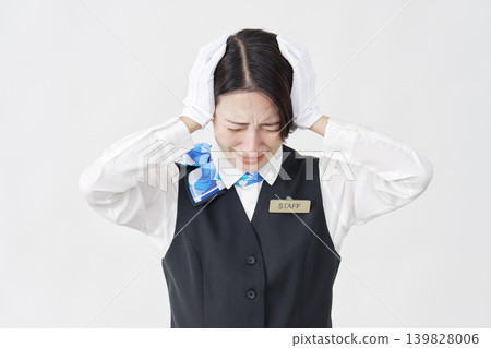 Female staff member, receptionist/bus guide, holding her head in her hands, against a white background. Female staff member, receptionist/bus guide, holding her head in her hands, against a white background. 139828006