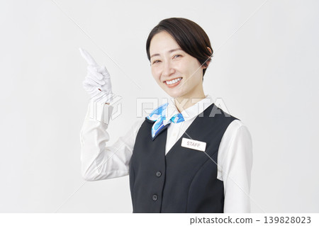 Female staff member pointing to the left; receptionist/bus guide; white background. Female staff member pointing to the left; receptionist/bus guide; white background. 139828023