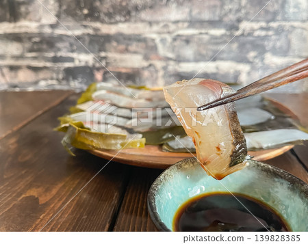 Spanish mackerel and bigfin reef squid cured in kelp. A dish where fresh sashimi is wrapped in kelp and aged. The Spanish mackerel is being lifted with chopsticks. Spanish mackerel and bigfin reef squid cured in kelp. A dish where fresh sashimi is wrapped in kelp and aged. The Spanish mackerel is being lifted with chopsticks. 139828385
