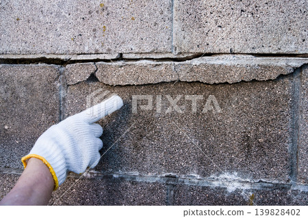 A concrete block wall with cracks due to age-related deterioration. A concrete block wall with cracks due to age-related deterioration. 139828402