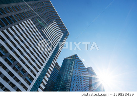 Modern high-rise residential buildings with glass facades against a clear blue sky. Modern high-rise residential buildings with glass facades against a clear blue sky. 139828459