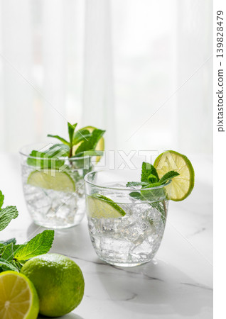 A fresh mojito with lime, mint and ice in glasses. Citrus lemonade or cocktail on a marble table A fresh mojito with lime, mint and ice in glasses. Citrus lemonade or cocktail on a marble table 139828479