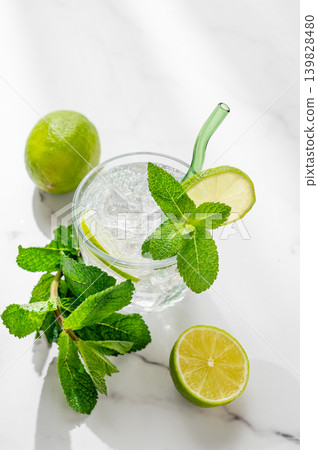 A fresh mojito with lime, mint and ice in glass. Citrus lemonade or cocktail on a marble table A fresh mojito with lime, mint and ice in glass. Citrus lemonade or cocktail on a marble table 139828480