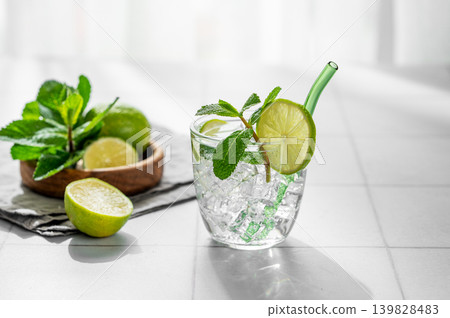 A fresh mojito with lime, mint and ice in glass. Citrus lemonade or cocktail on a table A fresh mojito with lime, mint and ice in glass. Citrus lemonade or cocktail on a table 139828483