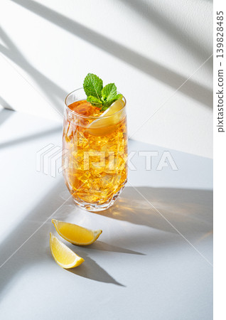Iced tea with lemon and mint in a glass on a light background with shadows 139828485