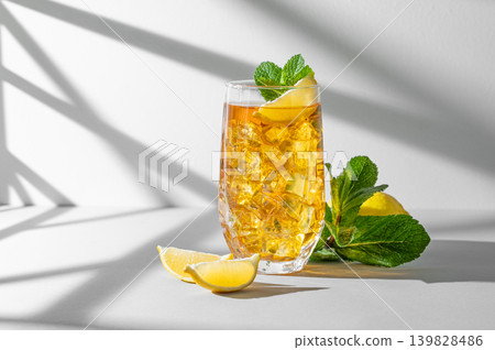Iced tea with lemon and mint in a glass on a light background with shadows 139828486