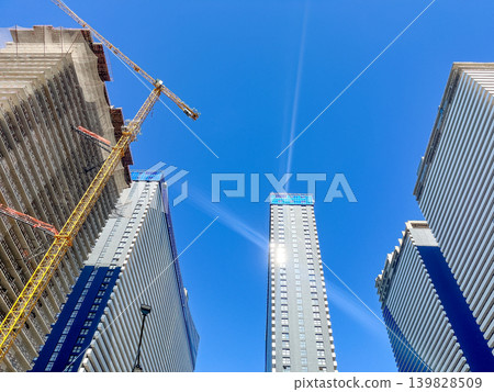 High-rise building under construction with tower crane against a clear blue sky. High-rise building under construction with tower crane against a clear blue sky. 139828509