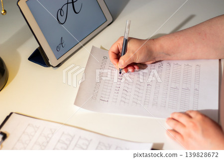 Person seated at desk deeply focused on writing in notebook. Physical engagement of motor skills Handwriting as brain training. Prevention of age related cognitive decline. Senior or adult practicing Person seated at desk deeply focused on writing in notebook. Physical engagement of motor skills Handwriting as brain training. Prevention of age related cognitive decline. Senior or adult practicing 139828672