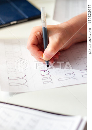 Physical over Digital concept. Woman training calligraphy at desk. Handwriting improves concentration and conceptual understanding better than digital notes. Perfect tool for mental clarity. Focus 139828675