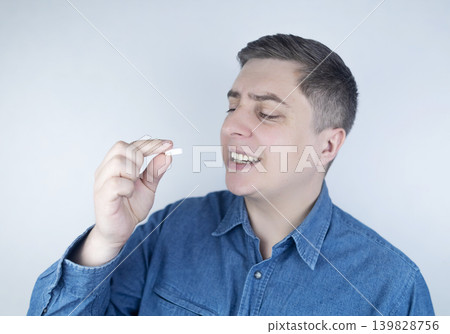 Man suffering from phagophobia struggling to swallow pill. Caucasian male looking anxious and scared before taking medication, experiencing fear of choking or swallowing difficulties.  139828756